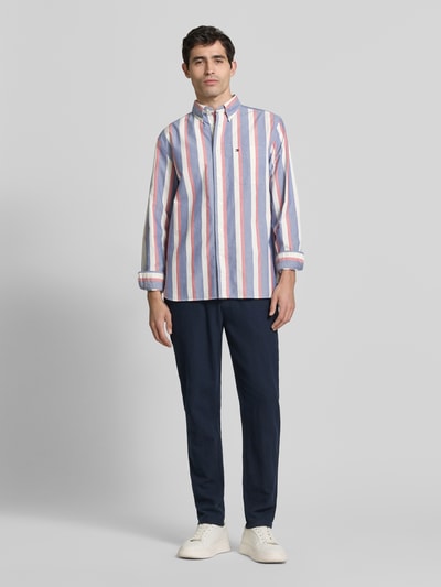 Männermodel trägt meerkleurig relaxed fit Vrijetijdsoverhemd uit puur katoen Model 'HERITAGE' van Tommy Hilfiger met all-over motief, button-downkraag, doorlopende knoopsluiting, logostitching, achterpas met cacharelplooi, lange mouwen met ronde 1-knoopsmanchet, licht afgeronde rompzoom, voorkant, ganzepenlichaamsopname.