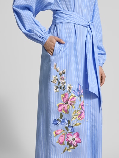 Vrouwenmodel draagt Regular Fit Maxikleid met floralem Print van Fynch-Hatton, puur katoen, bloemenprint, overhemdkraag, met lange mouwen, doorknoopsluiting, elastische mouwboorden, getailleerde pasvorm, afneembare stoffen band, ruglengte maat 36: 126 cm, borstwijdte maat 36: 57 cm, mouwlengte maat 36: 53 cm, detailopname zijkant.