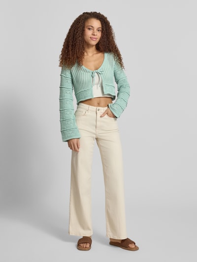 Frauenmodel trägt Regular Fit Strickjacke aus Baumwoll-Mix Modell 'NATALIE' von Only, Optik: Unifarben, Schnürung, Trompetenärmel, Materialverarbeitung: Ajour-Strick, Ganzkörperansicht von vorne.