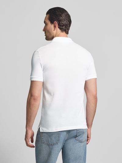 Männermodel trägt Slim Fit Poloshirt aus reiner Baumwolle von Lacoste in Optik: Unifarben, Piqué-Textur, Rückansicht, Ganzkörperansicht.