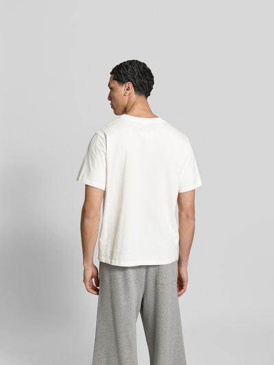 Männermodel trägt Relaxed Fit T-Shirt mit Logo-Patch von MM6 Maison Margiela aus reiner Baumwolle, weiß, Rückenlänge 80 cm, Ganzkörperansicht Rückansicht.