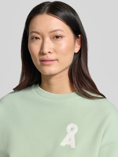 Frauenmodel trägt Oversized Sweatshirt aus reiner Baumwolle Modell 'BAMIKAA' von Armedangels, Optik: Unifarben, Logo-Stitching, Rundhals-Ausschnitt, Ärmelform: Kurzarm, Materialverarbeitung: Sweat, Nahaufnahme Oberkörper.