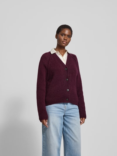 Frauenmodel trägt Strickjacke aus Alpaka-Mix mit Woll-Anteil von Closed in Dunkellila, V-Ausschnitt, Knopfleiste, Lockerer-Schnitt, Gerippte-Abschlüsse, Rückenlänge bei Größe S 58 cm, Ganzkörperansicht von vorne.