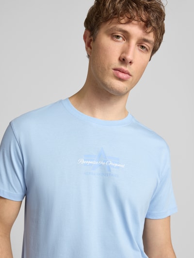 Męskimodel nosi T-Shirt mit Label-Detail od Alpha Industries, jasnoniebieski, bawełna, prosty krój, okrągły dekolt, długość tyłu 68 cm, rozmiar M. Nahaufnahme górnej części ciała.