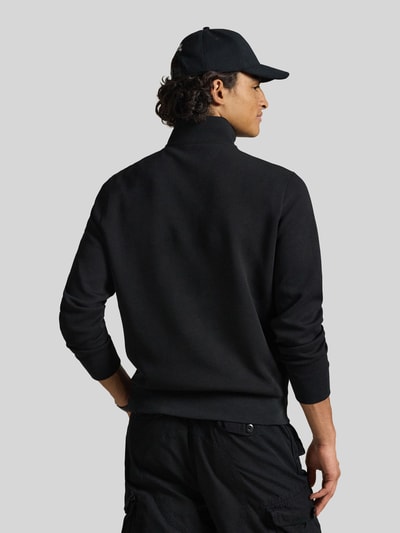Männermodel trägt Relaxed Fit Troyer aus Baumwoll-Mix von Polo Ralph Lauren in Schwarz, glatte Struktur, Ganzkörperansicht Rückansicht.
