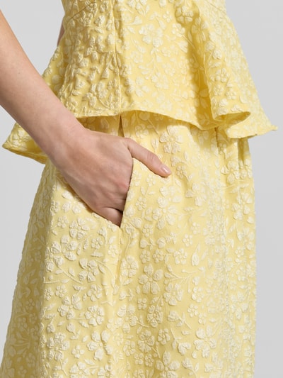 Kobieta nosi Ausgestellter Maxi-Rock mit Strukturmuster Modell 'FIONA' od Vero Moda, żółty, piqué jacquard, krój regular fit, detal kieszeni, zbliżenie na biodro.