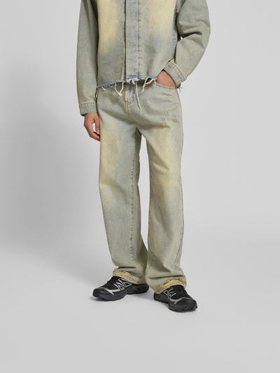 Männermodel trägt Wide Fit Jeans im Used-Look von Don’t Waste Culture, Reine Baumwolle, 5-Pocket-Design, Knopf- und Reißverschluss, beige-graue Farbtöne, Textur mit Used-Details, Ganzkörperansicht von vorne.