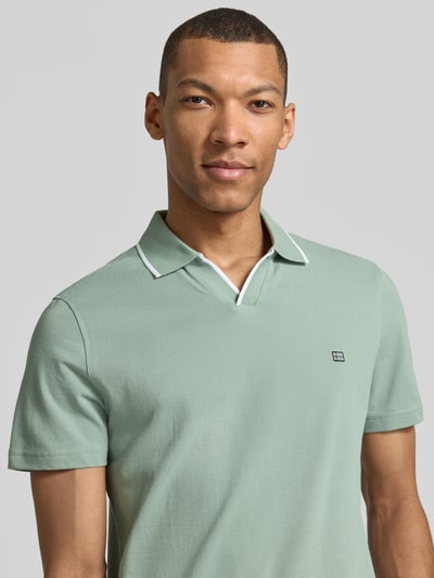 Männermodel trägt Modern Fit Poloshirt mit Logo-Stitching von Christian Berg Men aus Reine Baumwolle in Grün, Nahaufnahme Oberkörper. Rückenlänge bei Größe M: 71 cm, Polokragen.