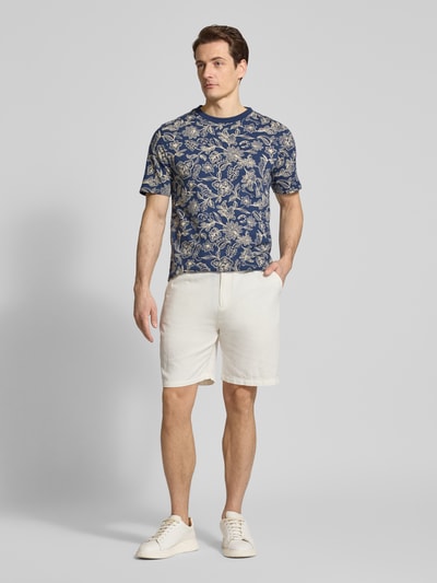 Männermodel trägt Shorts aus Baumwoll-Leinen-Mix Modell 'FAVE' von Scotch & Soda in Naturton, Regular Fit, elastischer Bund, Ganzkörperansicht von vorne. Kontext: Herren Shorts, Bundweite bei Größe 32: 42 cm, Innenbeinlänge 21 cm.