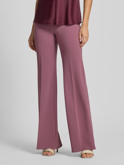 Frauenmodel trägt Flared Fit Stoffhose mit Bügelfalten von Rinascimento in Mauve, Material-Mix mit Stretch-Anteil, Nahaufnahme Unterkörper.