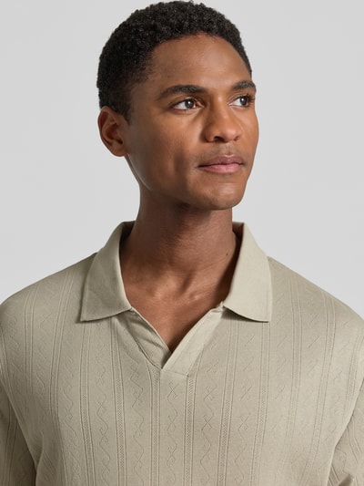 Männermodel trägt Regular Fit Poloshirt in Jaquard-Strick von Lindbergh in Beige, Reine Baumwolle, Label-Detail, Nahaufnahme Oberkörper.