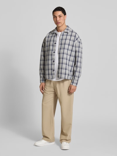 Männermodel trägt Relaxed Fit Freizeithemd mit Kentkragen und Label-Stitching von Pegador, kariertes Strukturmuster, helle Farben, Ganzkörperansicht von vorne