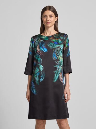 Frauenmodel trägt Relaxed Fit Kleid mit Foto-Print von Marc Cain, elastischer Material-Mix, knielang, Halbarm, Rundhals, Ganzkörperansicht von vorne.