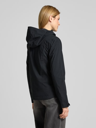 Frauenmodel trägt Regenjacke mit Omni-Tech™ ECO-Technologie von Columbia in Schwarz, mattes Material, verstellbare Elemente, Ganzkörperansicht Rückansicht.
