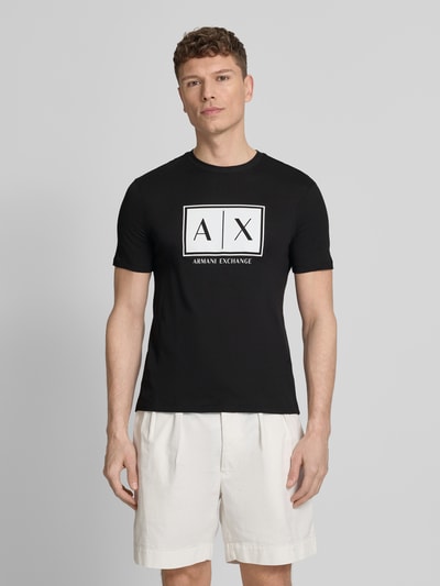 Mannenmodel draagt T-shirt met logo en ronde hals van ARMANI EXCHANGE in zwart, puur katoen, regular fit, ruglengte maat M 71 cm, vooraanzicht busteshot.