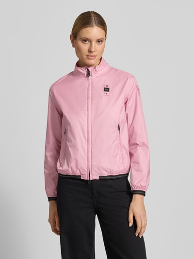 Kobieta modelka nosi różową kurtkę Jacke mit Zweiwege-Reißverschluss Modell 'ANNABEL' od Blauer Usa, krój regular fit, stójka, detale z logo, kieszenie zapinane na zamek błyskawiczny, długość tyłu w rozmiarze S: 58 cm, szerokość ramion w rozmiarze S: 42 cm, szerokość klatki piersiowej w rozmiarze S: 50 cm, długość rękawów w rozmiarze S: 60 cm; widok całej sylwetki z przodu