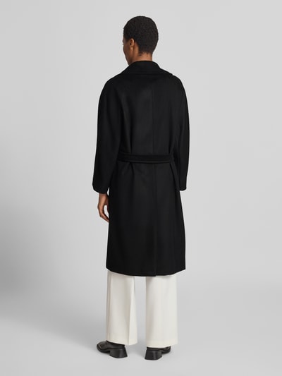 Frauenmodel trägt schwarzen Regular Fit Mantel aus reiner Schurwolle Modell 'RESINA' von Weekend Max Mara, Ganzkörperansicht Rückansicht.