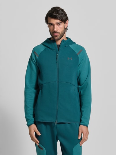 Männermodel trägt Regular Fit Jacke mit Kapuze Modell 'Unstoppable' von Under Armour, Elastischer-Material-Mix mit Baumwoll-Anteil, Logo-Print, Zweiwege-Reißverschluss, geteilte Känguru-Tasche, Farbe Petrol, elastische Abschlüsse, Rückenlänge 75 cm, Ärmellänge 57 cm, Ganzkörperansicht von vorne.