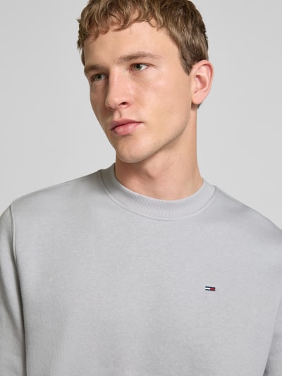 Männermodel trägt Regular Fit Sweatshirt aus Baumwoll-Mix von Tommy Jeans, Optik: unifarben, Logo-Stitching, Nahaufnahme Oberkörper.