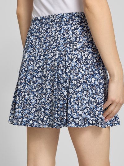 Frauenmodel trägt Mini-Skort aus reiner Viskose Modell 'NALA LIFE' von Only, Allover-Muster in Blau-Weiß, elastischer Bund, Nahaufnahme Rückansicht.