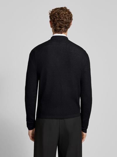 Männermodel trägt Regular Fit Strickjacke aus reiner Schurwolle von Emporio Armani, schwarze Farbe, gerippte Abschlüsse, Ganzkörperansicht Rückansicht.