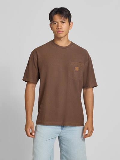 Männermodel trägt Regular Fit T-Shirt aus reiner Baumwolle Modell 'Loose Pocket' von Carhartt Work In Progress in Braun, Brusttasche, Ganzkörperansicht von vorne, Herren T-Shirt, Rückenlänge bei Größe M: 76 cm.
