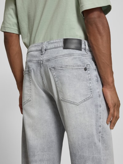 Männermodel trägt Tapered Fit Jeans aus Baumwoll-Mix Modell 'ARLO' von BOSS Orange, grauer Denim mit Label Patch, Nahaufnahme Rückansicht.