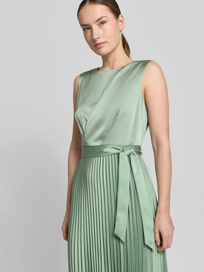 Kobiece modelka nosi Midikleid mit Plisseefalten und Bindegürtel von comma, zielony materiał mieszanka materiałów z dodatkiem streczu, linia a, plisy, wiązany pasek, szerokość w rozmiarze 36: 40 cm, długość tyłu 36: 35 cm, zbliżenie na górną część ciała z przodu