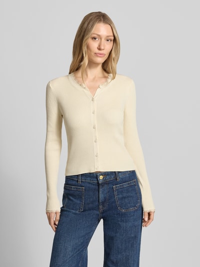 Frauenmodel trägt Slim Fit Strickjacke aus Viskose-Mix Modell 'WONDER' von Vero Moda, Optik: Unifarben, Spitzen-Besatz, Rippstrick, Rundhals, Langarm, Materialverarbeitung: Rippstrick, Farbe: Creme, Oberfläche fein strukturiert, Ganzkörperansicht von vorne.