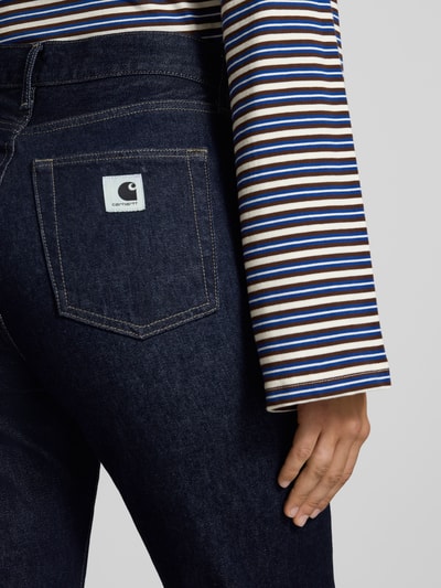 Frauenmodel trägt Slim Fit Jeans mit Knopfverschluss Modell 'Noxon' von Carhartt Work In Progress, dunkles Denim, 5-Pocket-Design, Nahaufnahme Rücken, Damen Jeans, Bundweite 40 cm, Innenbeinlänge 84 cm.