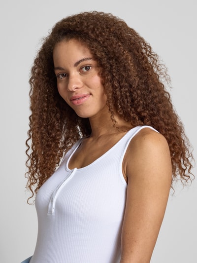 Modelka kobieca nosi Slim Fit Tank Top aus Bio-Baumwoll-Mix Modell 'KITTE' od Pieces, materiał w prążki, jednolity, zapięcie na guziki, szerokie ramiączka, dekolt Henley, biała, krój slim fit, zbliżenie na górną część ciała