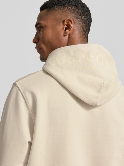 Männermodel trägt Regular Fit Hoodie aus reiner Baumwolle von Marc O'Polo in Beige mit Kapuze, Label-Schriftzug, Nahaufnahme Rückansicht.
