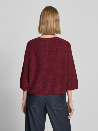 Frauenmodel trägt Strickjacke aus Alpaka-Mix mit Leinen-Anteil Modell 'Thora' von MOS MOSH in dunklem Rot und Jeans, Ganzkörperansicht Rückansicht. Gerade Passform, 3/4-Arm, weiche Textur, Rückenlänge ca. 50 cm, Ärmellänge ca. 19 cm.