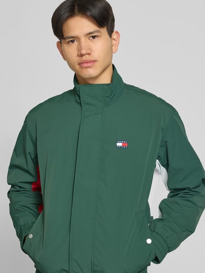 Männermodel trägt Regular Fit Blouson mit Logo-Stitching von Tommy Hilfiger in Grün, Optik: Unifarben, Satin, Ganzkörperansicht von vorne.