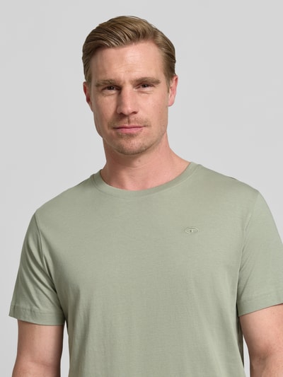 Męski model nosi Regular Fit T-Shirt aus reiner Baumwolle von Tom Tailor, efekt: jednolity kolor, wyhaftowane logo, okrągły dekolt, krótki rękaw, dżersej, czysta bawełna, zbliżenie na górną część ciała.