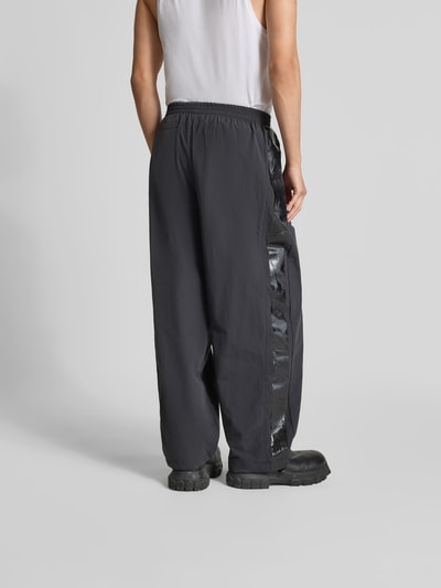 Männermodel trägt Sweatpants mit elastischem Bund von VETEMENTS, Relaxed Fit, Wide Leg, schwarze Farbe, Ganzkörperansicht Rückansicht.