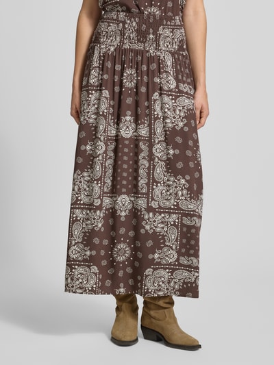 Vrouwenmodel draagt donkerbruine dames maxi rok met witte paisley patronen, Ausgestellter Maxi-Rock aus reiner Viskose Modell 'SAKI AMBEL' van Only, ganzlichaamsaanzicht van voren.