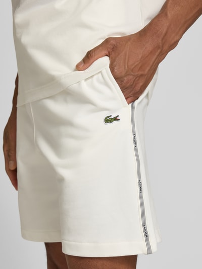 Männermodel trägt Regular Fit Sweatshorts aus reiner Baumwolle von Lacoste, Optik: Unifarben, Logostreifen, Label-Patch, Nahaufnahme Oberschenkel.