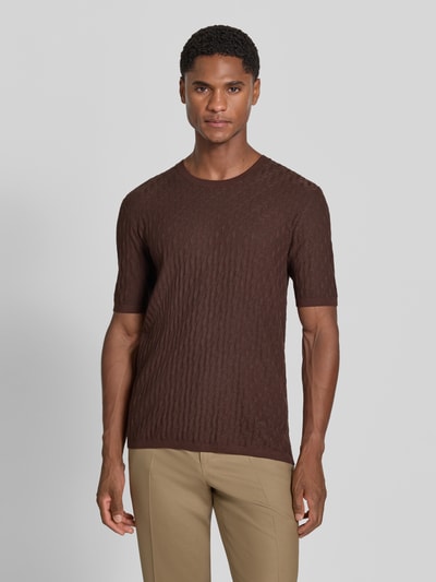 Männermodel trägt T-Shirt aus Viskose-Mix in Strick-Optik von Emporio Armani in Braun, schmale Passform, gerippte Abschlüsse, kurzärmelig, Ganzkörperansicht von vorne.