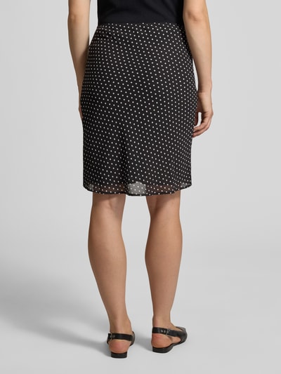 Frauenmodel trägt Minirock im Allover-Look Modell 'Mindie' von Neo Noir, schwarz mit weißen Punkten, Chiffon, Ganzkörperansicht Rückansicht. Bundweite 40 cm, Gesamtlänge 61 cm.