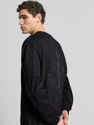 Männermodel trägt Oversized Sweatshirt aus Baumwolle von Don’t Waste Culture in Schwarz mit Florale-Stickereien, elastische Abschlüsse, Rückenlänge 66 cm, Ganzkörperansicht Rückansicht.