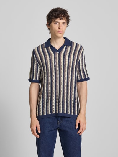 Männermodel trägt Regular Fit Poloshirt aus Baumwoll-Mix Modell 'THUE' von Only & Sons mit gestreiftem Allover-Muster, Lochstrickstruktur, kurze Ärmel, Polokragen, V-Ausschnitt, Farben Blau, Beige, Ganzkörperansicht von vorne.