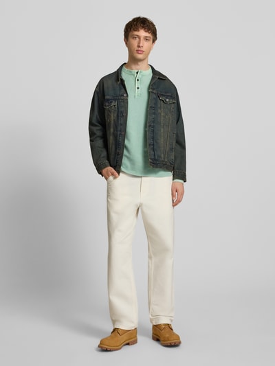 Męski model nosi Longsleeeve mit Knopfleiste od Superdry w kolorze miętowej zieleni, z czystej bawełny, krój regular fit, okrągły dekolt, listwa z guzikami, długość pleców w rozmiarze M: 72 cm, pełny widok z przodu.