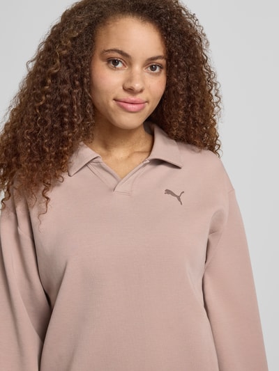 Frauenmodel trägt Relaxed Fit Poloshirt mit Lyocell-Anteil von PUMA in Beige, Logo-Detail, Polo-Kragen, Langärmelig, Elastischer-Material-Mix, Nahaufnahme Oberkörper.
