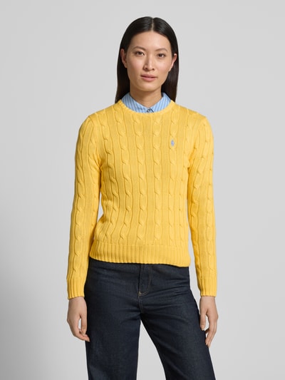 Frauenmodel trägt Regular Fit Strickpullover aus reiner Baumwolle Modell 'JULIANNA-LONG' von Polo Ralph Lauren in Optik: Unifarben mit Zopfmuster, Kragenform: Crew Neck, Ärmelform: Langarm, Ärmelabschluss und Rumpfabschluss: gerippt, Materialverarbeitung: Strick, Farbe Gelb, Ganzkörperansicht von vorne.
