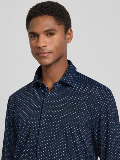 Mannenmodel draagt slim fit zakelijk overhemd met kentkraag model 'KENNO' van HUGO in donkerblauw met witte stippen, zakelijk overhemd, Nahaufnahme bovenlichaam.