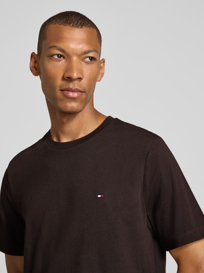Männermodel trägt Regular Fit T-Shirt aus reiner Baumwolle von Tommy Hilfiger in Dunkelbraun, glatte Textur, Nahaufnahme Oberkörper