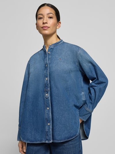 Vrouwenmodel draagt Relaxed Fit Jeansblouse uit katoen-lyocell-mix van Tommy Hilfiger in denimlook met gestikt logo, doorlopende knoopsluiting, maokraag, mouwboorden en afgeronde rompzoom, voorkant volledig zichtbaar, Ganzkörperansicht von vorne.