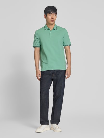 Männermodel trägt Regular Fit Poloshirt mit Logo-Stitching von bugatti in Grün, Reine Baumwolle, Polokragen, Kurze Knopfleiste, Ganzkörperansicht von vorne.