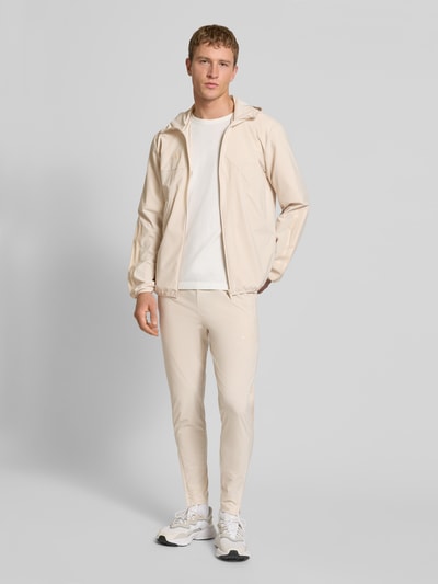 Mężczyzna model nosi Jogpants mit elastischem Bund od adidas Sportswear, materiał z dodatkiem stretchu, prosty krój, elastyczny pas, tunel, nadruk z logo, długość nogawki wewnętrznej w rozmiarze M: 71 cm, jasny beż, pełny widok z przodu.